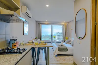 a kitchen with a counter and a living room with a couch at Santa Marina Apartments and Beach Club by Xarm Apartments in Santa Marta