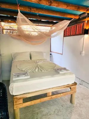 a bed in a room with a mosquito net at El Hamaquero Hostal EcoNativo in Isla Grande