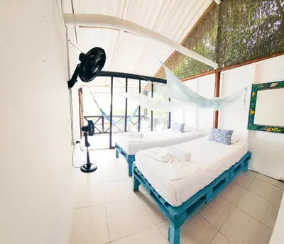 two beds in a room with a window at El Hamaquero Hostal EcoNativo in Isla Grande