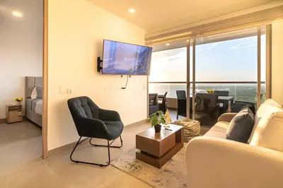 a living room with a couch and a chair and a tv at Santa Marina Santa Marta - By INMOBILIARIA VS in Santa Marta