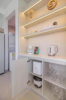 a kitchen with white cabinets and shelves with wine glasses at Luxury a 100 Mts del Mar en Edificio SeaWay in Cartagena de Indias