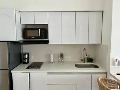 a kitchen with white cabinets and a sink and a microwave at cartagena beach resort in Cartagena de Indias