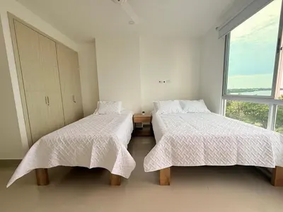 two beds in a white room with a window at Hermoso Apartamento Frente al Mar 3 Habitaciones AR54 in Coveñas