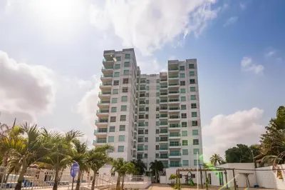 a tall building with palm trees in front of it at Hermoso Apartamento Frente al Mar 3 Habitaciones AR54 in Coveñas