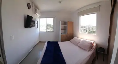a small bedroom with a bed and two windows at Piso 2206 Mirador de Cartagena in Cartagena de Indias