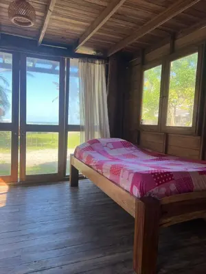 a bedroom with a bed in a room with windows at CARPE DIEM oceanfront cabin private beach in San Bernardo del Viento
