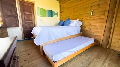 two beds in a room with wooden walls at Cabaña Punta Helvetica in San Antero