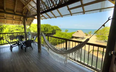 a hammock on a porch with a view of the ocean at Cabaña Punta Helvetica in San Antero