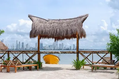 a beach with benches and a straw umbrella and the water at Cabaña privada con Jacuzzi a solo un minuto de la playa in Isla de Tierra Bomba