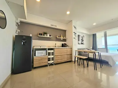 a kitchen with a refrigerator and a table in a room at Apartasuit Resort CTG Beach con vista al mar- central 5 min aeropuerto in Cartagena de Indias