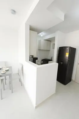 a white kitchen with a black refrigerator and a table at VIP Cartagena Close to the 415 Wall in Cartagena de Indias