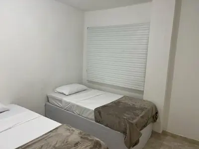 two beds in a white room with a window at Cartagena Visible Hostal in Cartagena de Indias