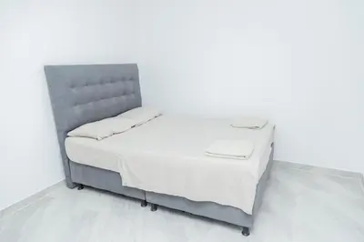 a bed with a gray headboard in a white room at Apartamentos King Arthur in Punta Seca