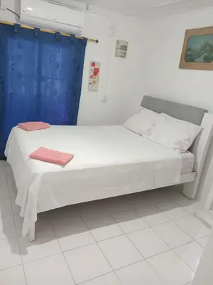 a white bed in a room with a blue curtain at shanty guest hostal in Cartagena de Indias