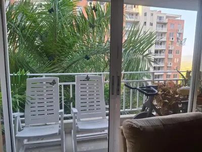 two chairs on a balcony with a view of a palm tree at APARTAMENTO-Miramar in Barranquilla
