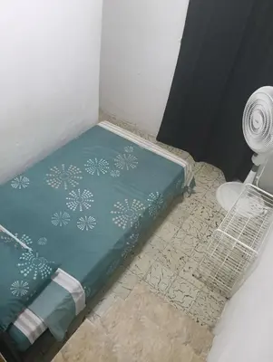 a small bed in a room with a fan at Habitación con medio baño en el barrio ciudad jardín Barranquilla in Barranquilla