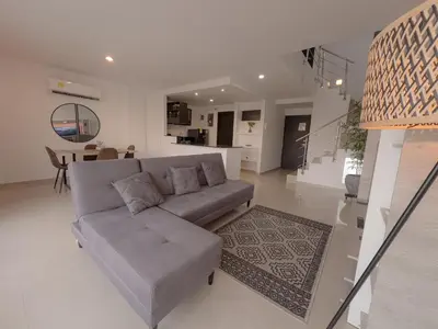 a living room with a gray couch and a kitchen at Stunning Caribbean-Inspired PH next to Viva Mall in Barranquilla