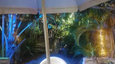 a table with an umbrella and some palm trees at cabaña frente al mar de cartagena in Cartagena de Indias