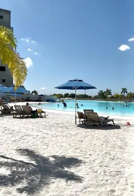 a beach with chairs and an umbrella and the water at Baia Kristal Cartagena in Cartagena de Indias