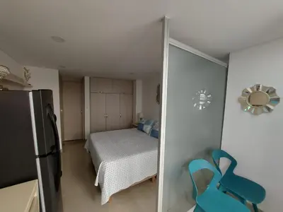 a small bedroom with a bed and a refrigerator at Apartaestudio al frente del Mar in Cartagena de Indias