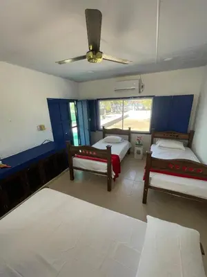 a room with three beds and a ceiling fan at Villa Liz in Puebloviejo