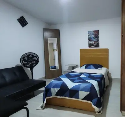 a bedroom with a blue and white bed and a couch at Casa playa salgar in Puerto Colombia