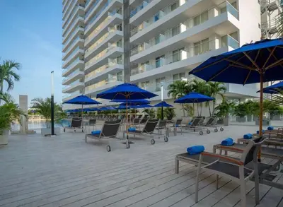 a patio with blue umbrellas and chairs and tables at Apartaestudio con hotel y playa in Santa Marta