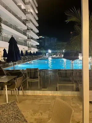 a swimming pool at night with chairs and umbrellas at Apartaestudio con hotel y playa in Santa Marta