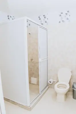a white bathroom with a shower and a toilet at Hotel Ibatama in Cartagena de Indias