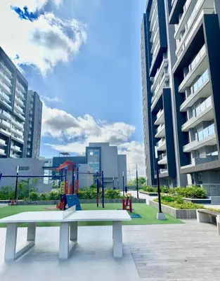 a white bench with a playground in a city at Apartamento cerca Malecón y CC mall plaza in Barranquilla