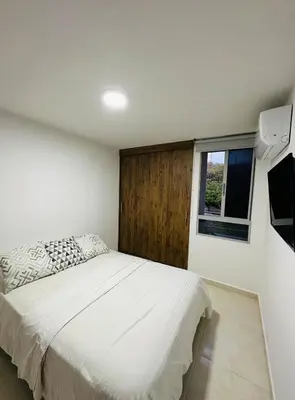 a bedroom with a white bed and a window at cool and quiet apartment in front of the urban forest in Barranquilla
