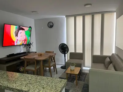 a living room with a couch and a tv on the wall at Alameda del rio Turpial in Barranquilla