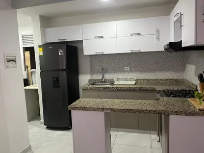 a kitchen with white cabinets and a black refrigerator at Alameda del rio Turpial in Barranquilla
