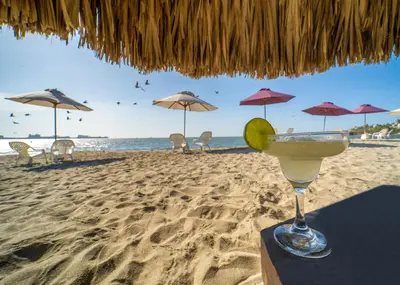 a margarita in a glass sitting on the beach at Hotel Santorini Casablanca Resort in Santa Marta