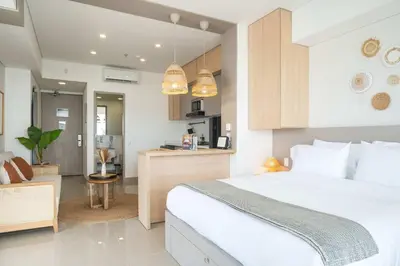 a bedroom with a large white bed and a kitchen at Elegant Beachview 1BR with Balcony in Crespo in Cartagena de Indias
