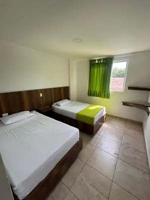 a bedroom with two beds and a window with green curtains at Hotel Palma Grande By Origen