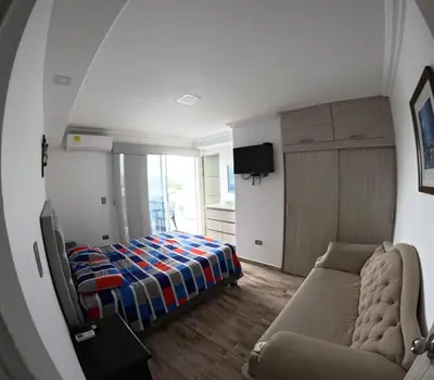 a bedroom with a bed and a couch and a mirror at Viewpoint apartment near the Historic Center in Cartagena de Indias