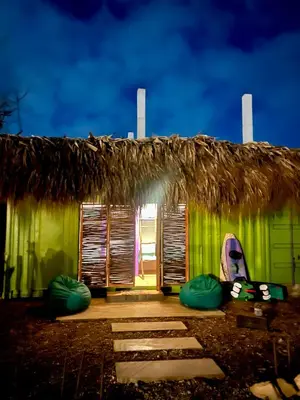 a green hut with windows and a thatched roof at Riders Shared Room en Mojarra Beach in Salina de Rey