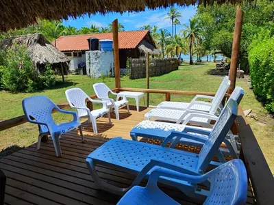 a group of chairs sitting on a wooden deck at Cabaña de playa 6 personas con cocina y kiosko privado in Moñitos