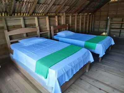 two beds in a room with wooden floors at Cabaña de playa 6 personas con cocina y kiosko privado in Moñitos