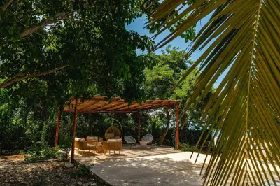a pavilion with tables and chairs under a tree at Paradise Private Kaimari Ocean Villa in Cartagena de Indias