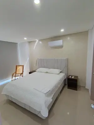 a bedroom with a white bed and a chair at 612 Beautiful Apartment Near the Walled City in Cartagena de Indias