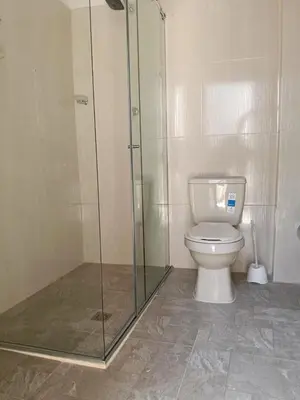 a bathroom with a toilet and a glass shower at Apartamento cerca a la playa y al aeropuerto in Santa Marta