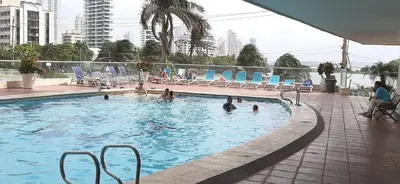 a swimming pool with chairs and people in the water at Beatifull apartment near Hilton hotel in Cartagena de Indias