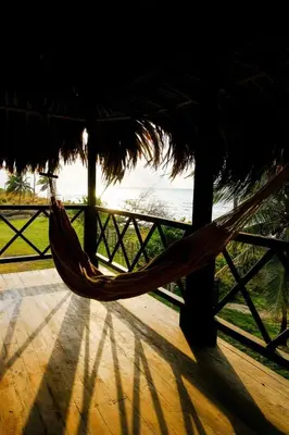 a hammock in a straw hut with a view of the ocean at Sarao Mar in Moñitos