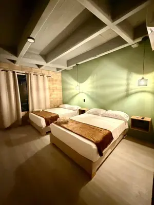 a bedroom with two beds and a green wall at Aira Hotel in Coveñas