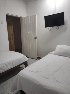 a bedroom with two beds and a flat screen tv on the wall at Hotel WK Casa de Hospedaje in Barranquilla