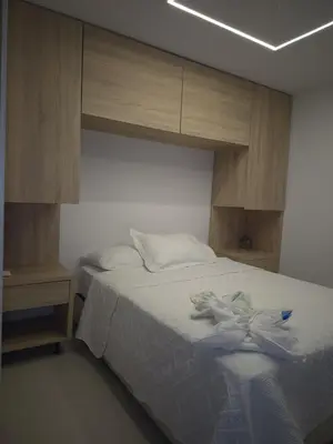 a bedroom with a white bed with wooden cabinets at Precioso apartamento cerca del mar in Cartagena de Indias