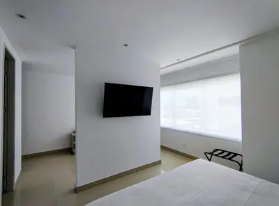 a white bedroom with a television on a wall at Apartasuites Amoblados Norte de Barranquilla-Atlantis Suites in Barranquilla