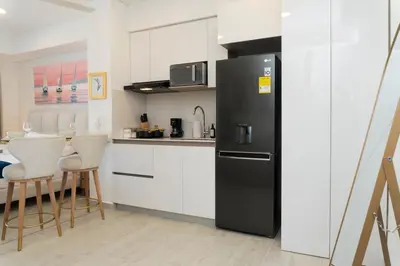 a kitchen with a black refrigerator and white cabinets at Luxury Apartment Suite Lake View 2 min Airport in Cartagena de Indias